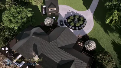 Straight-down aerial of the lodge roof, circular motor court with a planted island, and the rear deck over the lake