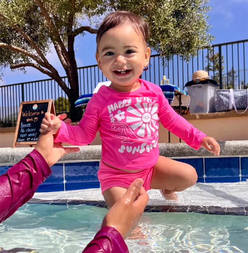 Toddler at pool edge with parent
